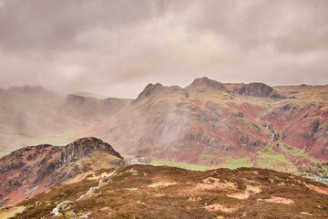 The Langdale Pikes seen through light cloud and rain from the summit of Lingmoor Fell, Lake District, UK