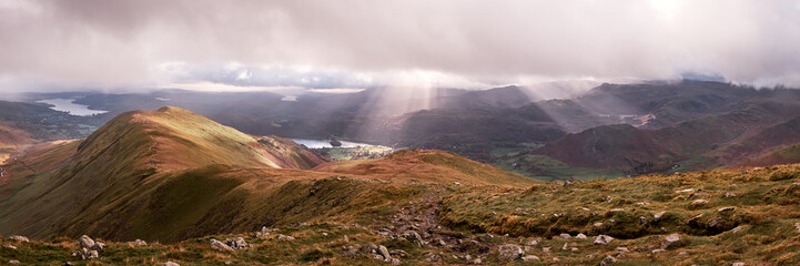 Panorama of shafts of sunlight breaking thorugh clouds on the descent from Great Rigg on the...