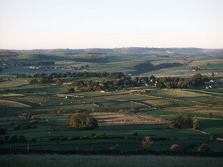 View over fields with sheep to the village of Foolow, from Eyam Edge, Bretton, Peak District, UK