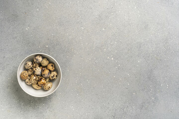 Quail eggs in white bowl on gray speckled surface minimalist design