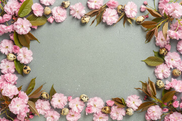 Spring floral frame with pink blossoms and quail eggs on textured background
