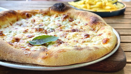 Freshly baked cheese pizza with basil on wooden table