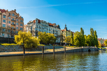 A view from the Vltava river towards colourful buildings on the west bank in Prague in springtime