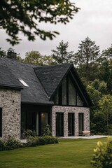 Modern stone house nestled in a lush green landscape with large windows and a sleek design, surrounded by trees on a cloudy day
