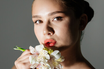 Close-up of a beautiful woman with glowing skin posing in a studio in dim lighting. Ideal for...