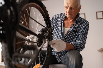 Active senior man repairing bicycle at home. cycling leisure. Retired male home mechanic with...