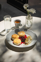 Portion of curd pancakes syrniki with berry jam and sour cream