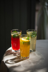 Three glasses of fresh lemonade beverages with lemon and mint
