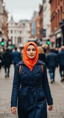 Fototapeta premium Confident adult female in orange hijab walking through busy city street
