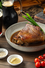 Portion of baked pork knuckle with sauce and spring onion