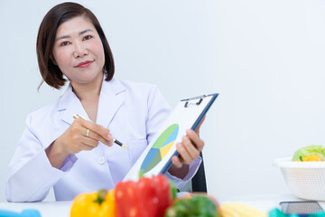 Nutritionist explaining diet plan with fresh vegetables on table