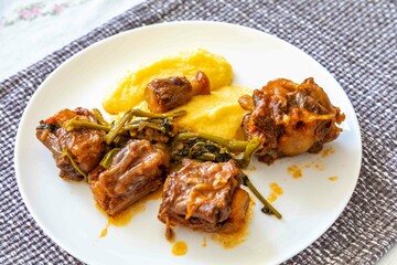 Delicious Brazilian food, oxtail stew with watercress and polenta, a gourmet dish on a white plate