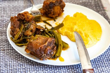 Delicious Brazilian food, oxtail stew with watercress and polenta, a gourmet dish on a white plate