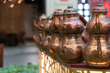 Beautiful copper Turkish coffee pots lined up in a charming store display. Copy space.
