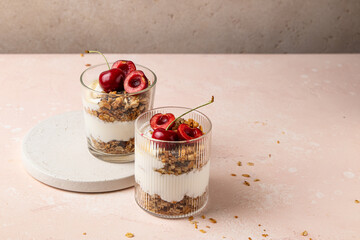 Cherry yogurt parfaits. Granola with fresh cherries, yogurt, chia and honey on the pink table. Finger foods. Selective focus, copy space.