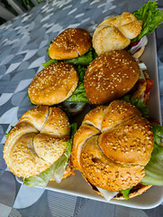 A tray of six sesame seed buns with lettuce and meat. The bun is shaped like a spiral and is topped with lettuce and meat