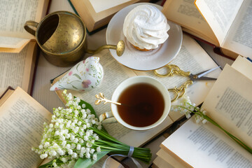 A cup of tea and a bouquet of lilies of the valley, books on a spring morning.