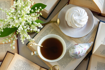 A cup of tea and a bouquet of lilies of the valley, books on a spring morning.