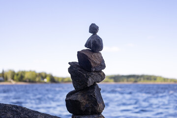 A balanced stack of stones stands near the shore, with calm water in the background