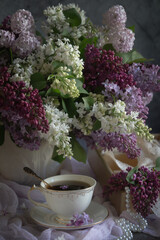 A bouquet of lilacs on the table and a cup of tea.