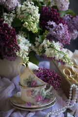 A bouquet of lilacs on the table and a cup of tea.