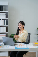 Asian Woman Working at Desk with Laptop and Phone