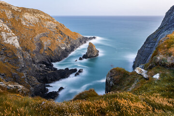 A serene coastal landscape, rugged cliffs and calm waters, ideal for relaxation
