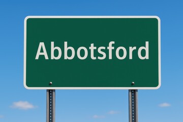 Green road sign reading "Abbotsford" stands under a vivid blue sky, marking entry or direction to the Canadian city.