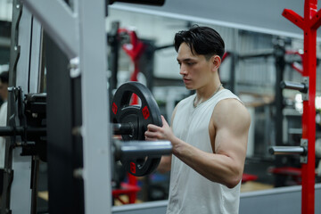 Young Sportsman Adding Weights to Barbell in Gym
