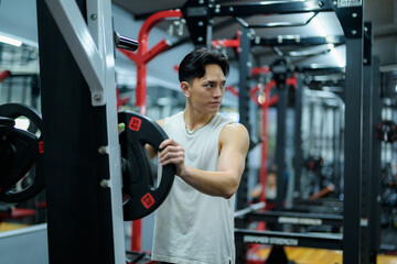 Sportsman adding weights on barbell getting ready for training