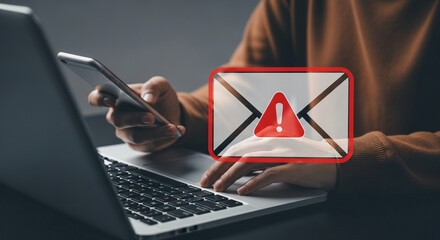 Person using laptop and phone with email warning sign overlay indicating possible phishing threat