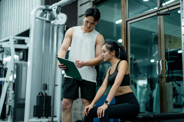 Fototapeta premium Personal trainer showing training schedule to sportswoman in gym