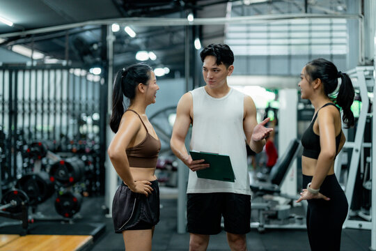 Personal trainer explaining training schedule to two women in the gym