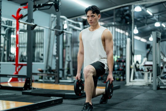 Asian athlete performing lunges with weights in gym - Powered by Adobe