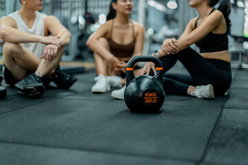Athletes resting after workout with kettlebell in gym