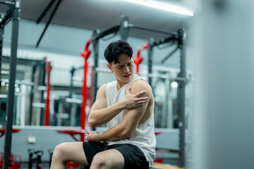 Young sportsman suffering shoulder pain during workout at gym
