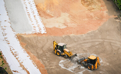 Two tractors leveling gravel at a construction site, preparing for park or infrastructure...