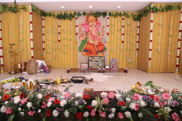 simple Hindu stage décor with Lord Ganesha as the backdrop in a golden theme