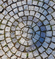 Intricate circular cobblestone pattern with natural grass accents for artistic and architectural...
