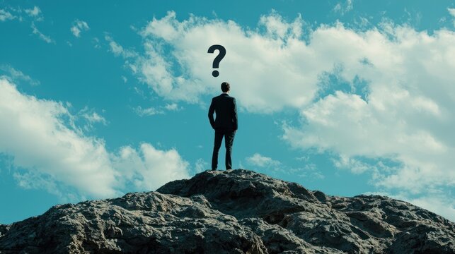 A man standing on a rocky outcrop with a question mark above his head, against a blue sky with white clouds. - Powered by Adobe