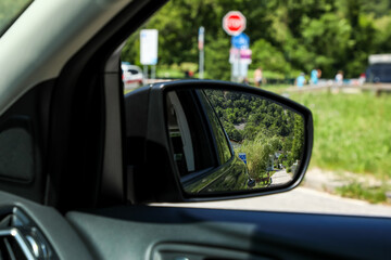 The driver looks into the side rearview mirror of the car to see all road users and at the same...