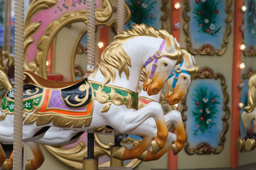 Close-up of ornate carousel horses with golden details and vibrant colors, evoking nostalgia and joy at a fairground or amusement park.