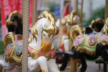 Close up of a white carousel horse with golden and pink accents. Amusement park ride detail for childhood fun and nostalgic concept.