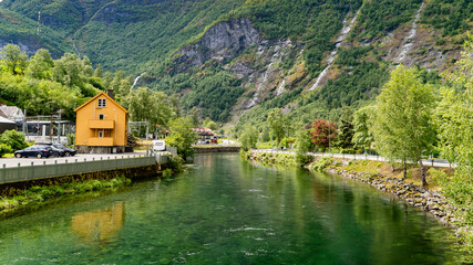 Fototapeta premium Flam river flowing past traditional Norwegian buildings and mountains