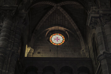 Matera, Italy. Stained glass rose window inside the Church of San Giovanni Battista in Matera. Illuminated in the dark Romanesque interior with stone arches and columns.