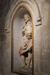 Matera, Italy. Statue of St. John the Baptist in a niche of the Church of San Giovanni Battista, Sassi of Matera, Italy. Worn colors and sacred symbolism in a Romanesque setting. Vertical.