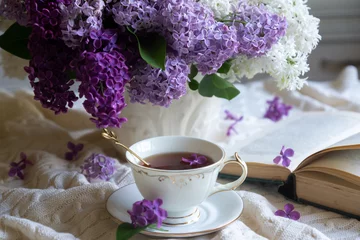 Fototapete Lila A bouquet of lilacs on the table and a cup of tea.  © ostapenkonat