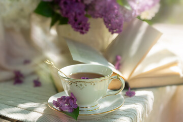 A bouquet of lilacs on the table and a cup of tea.