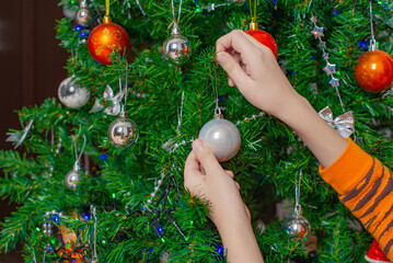 Christmas ball in the hands of a boy in a tiger costume. High quality photo