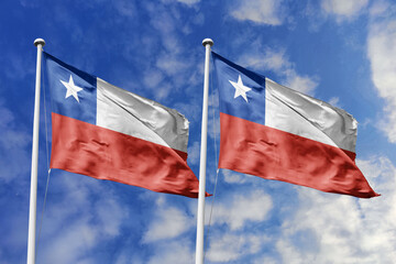 Two Chilean Flags Waving Proudly Against a Bright Blue Sky with Clouds, Symbolizing National Identity and Patriotism